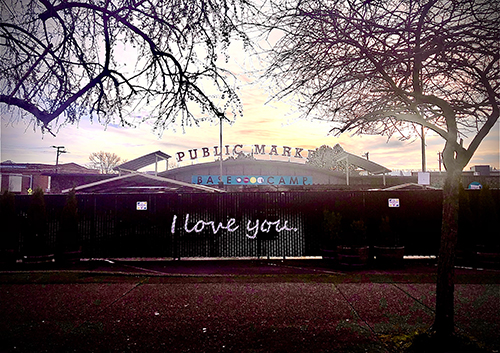 Fenced view of a City Public Market at sunset with a handwritten sign saying I love you.