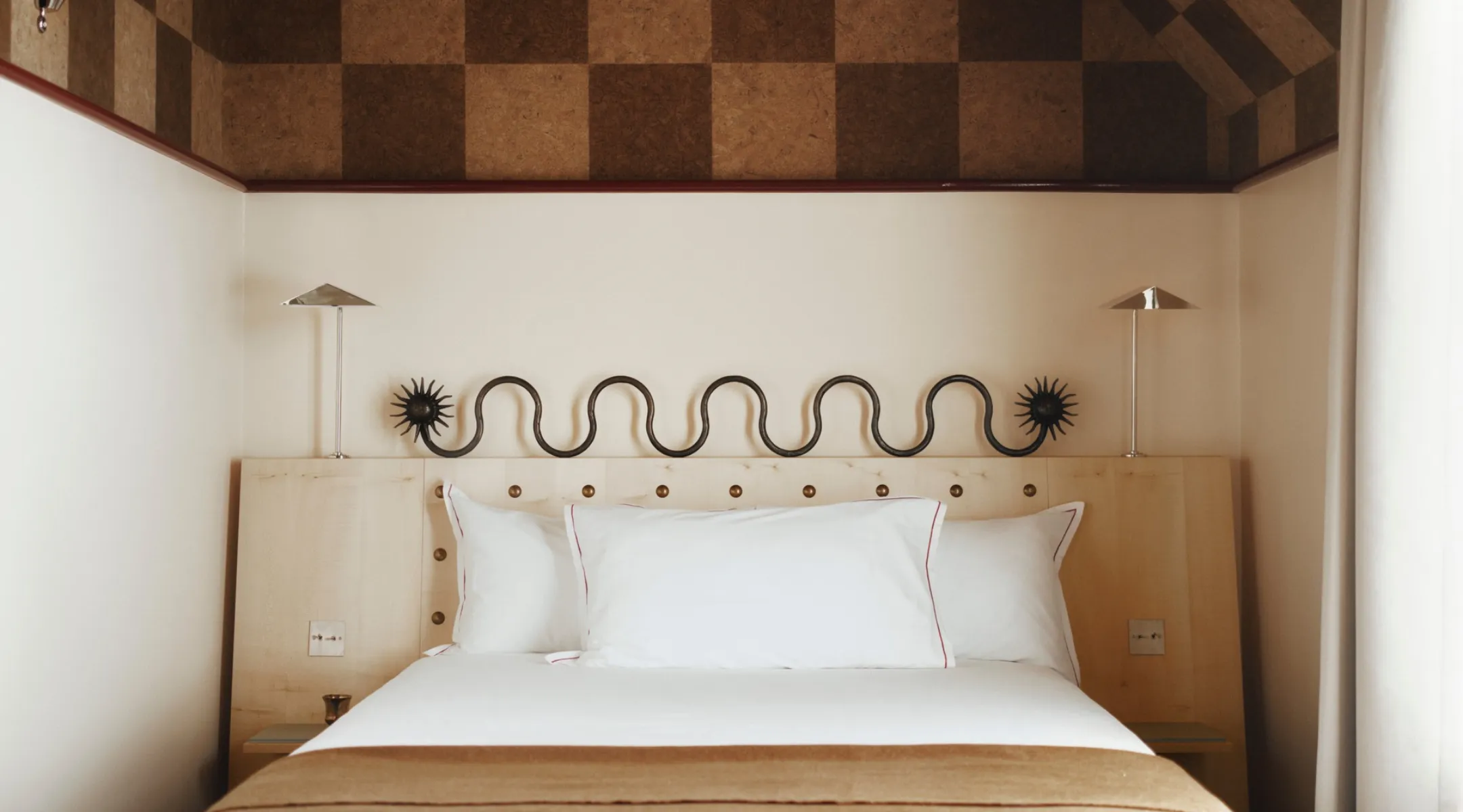 Chambre design de l'Hôtel Luxia à Montmartre, lit blanc et tête de lit en bois clair sous un plafond en liège à damier