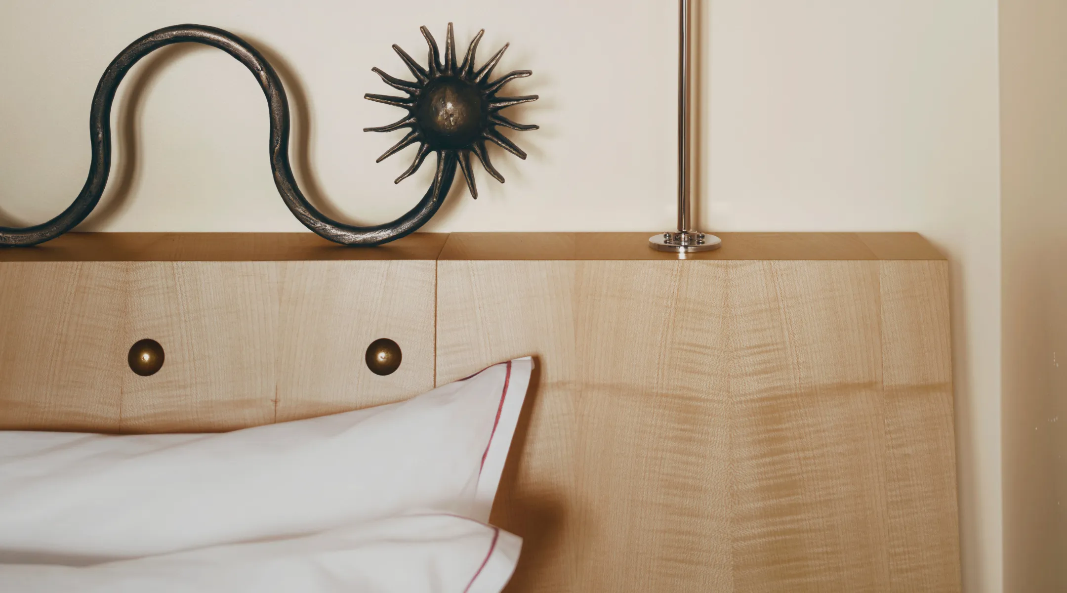 Blond wood headboard and wrought-iron sun ornament, Hotel Luxia in the press, Montmartre