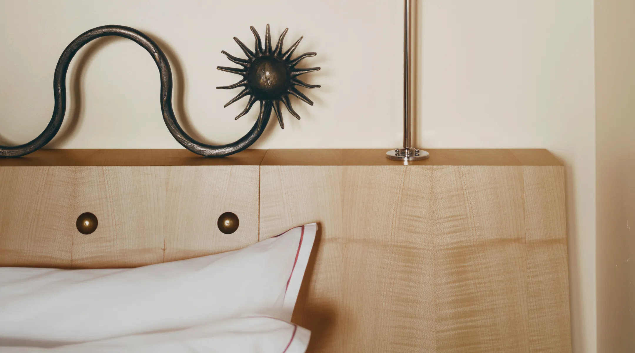 Blond wood headboard and wrought-iron sun ornament in a Hotel Luxia room in Montmartre