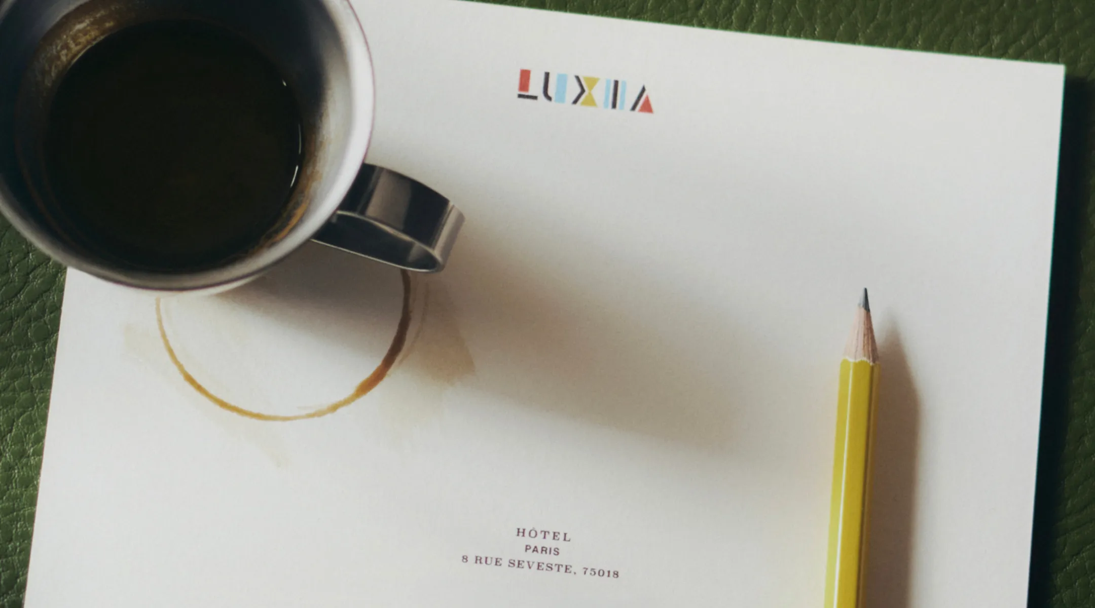 Papier à lettres de l'Hôtel Luxia, 8 rue Seveste à Paris 18e, avec une tasse de café et un crayon jaune