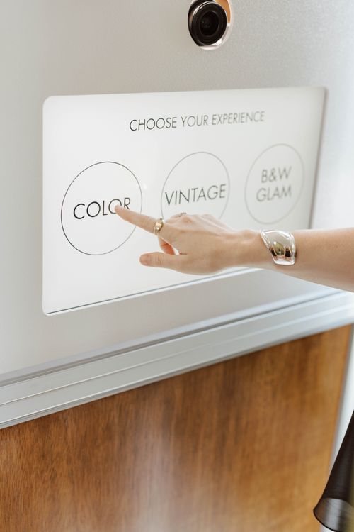 Hand with rings and bracelet selecting 'COLOR' option on a touch screen with three photo style choices.