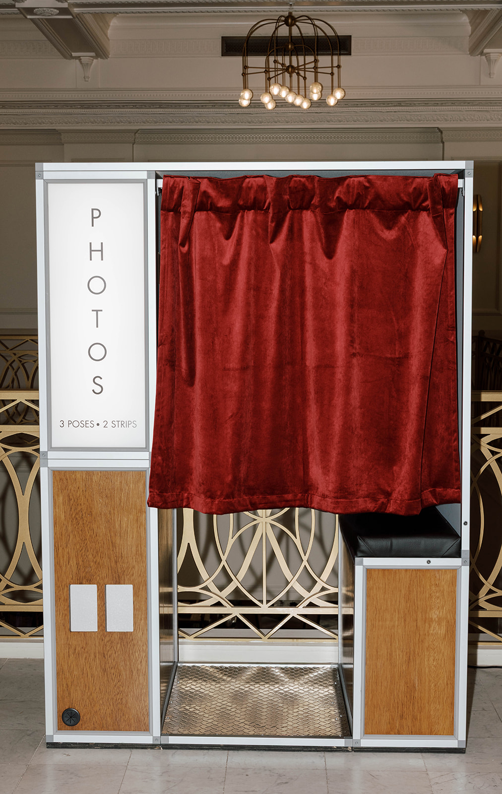 Photo booth with closed red velvet curtain, wooden panels, and text reading 3 poses, 2 strips.