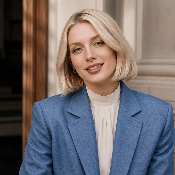 Blonde woman with short hair in a blue blazer and white blouse smiling at the camera.
