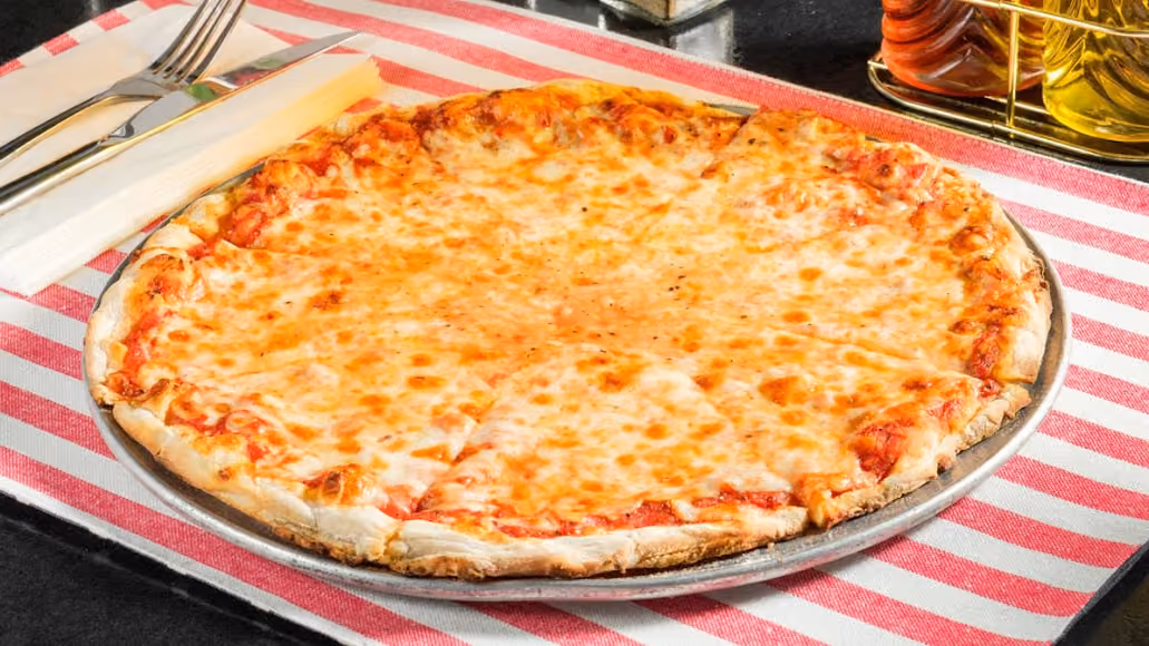 A cheese pizza sliced into six pieces on a metal tray with a fork and knife on a striped cloth.