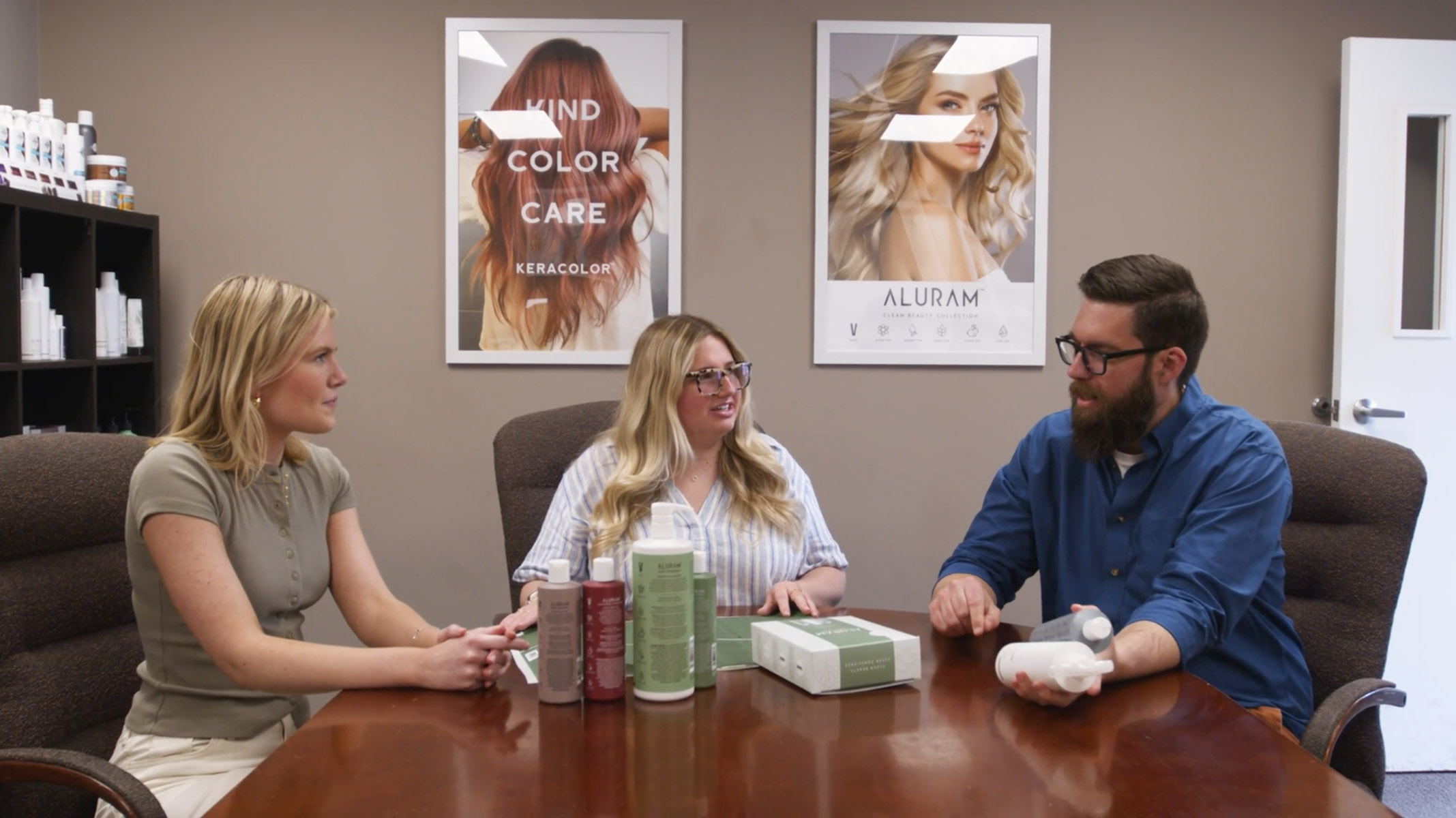 Three team members reviewing Keracolor and Aluram products around a conference table