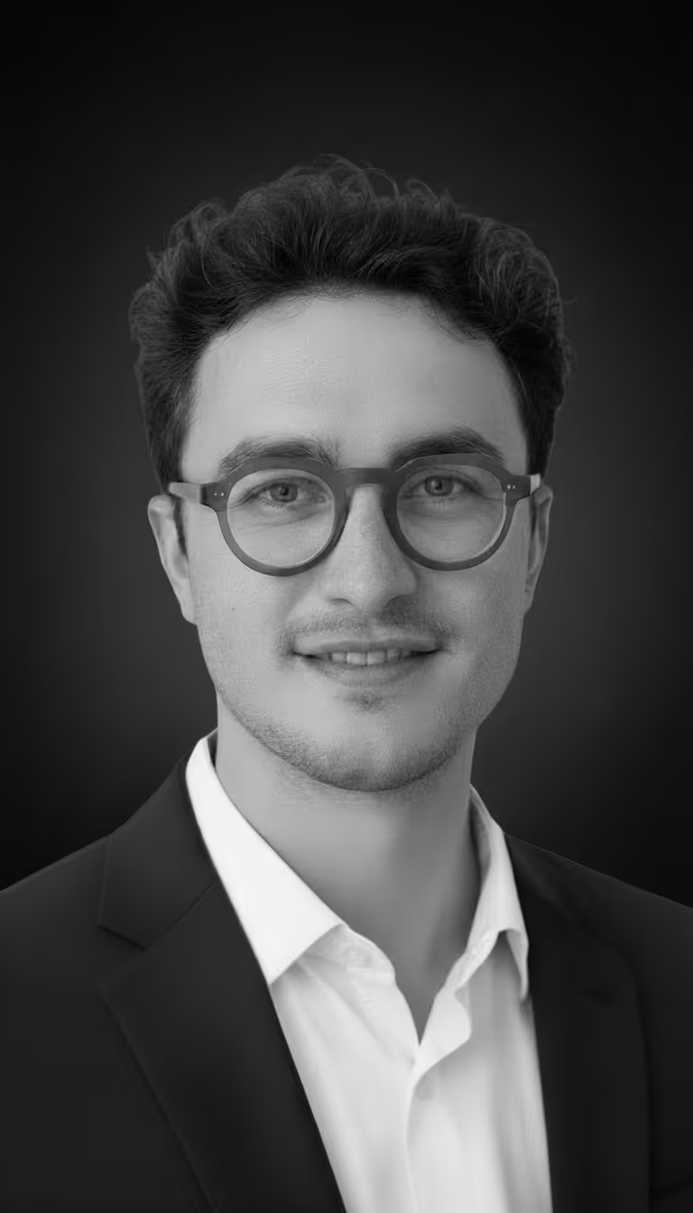 Porträt eines Mannes mit kurzen braunen Haaren, Brille, weißem Hemd und dunkelblauem Sakko.