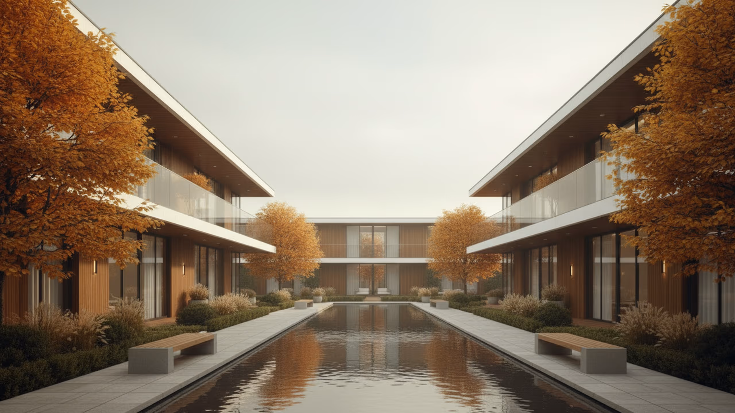 Moderner Innenhof mit Teich, Bänken, orangefarbenen Herbstbäumen und Gebäude mit Glasbalkonen.