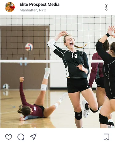 Female volleyball player in black jersey celebrates while an opponent falls on the court behind the net.