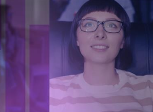 Smiling woman with glasses and short dark hair wearing a striped shirt sitting indoors.