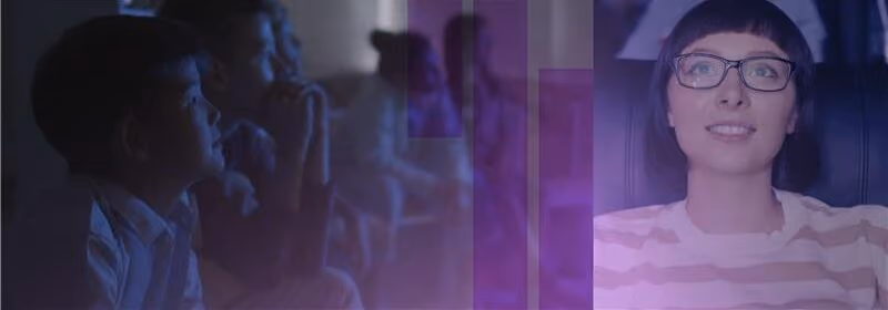 Smiling woman with glasses watching with children in dim light, purple overlay on image.