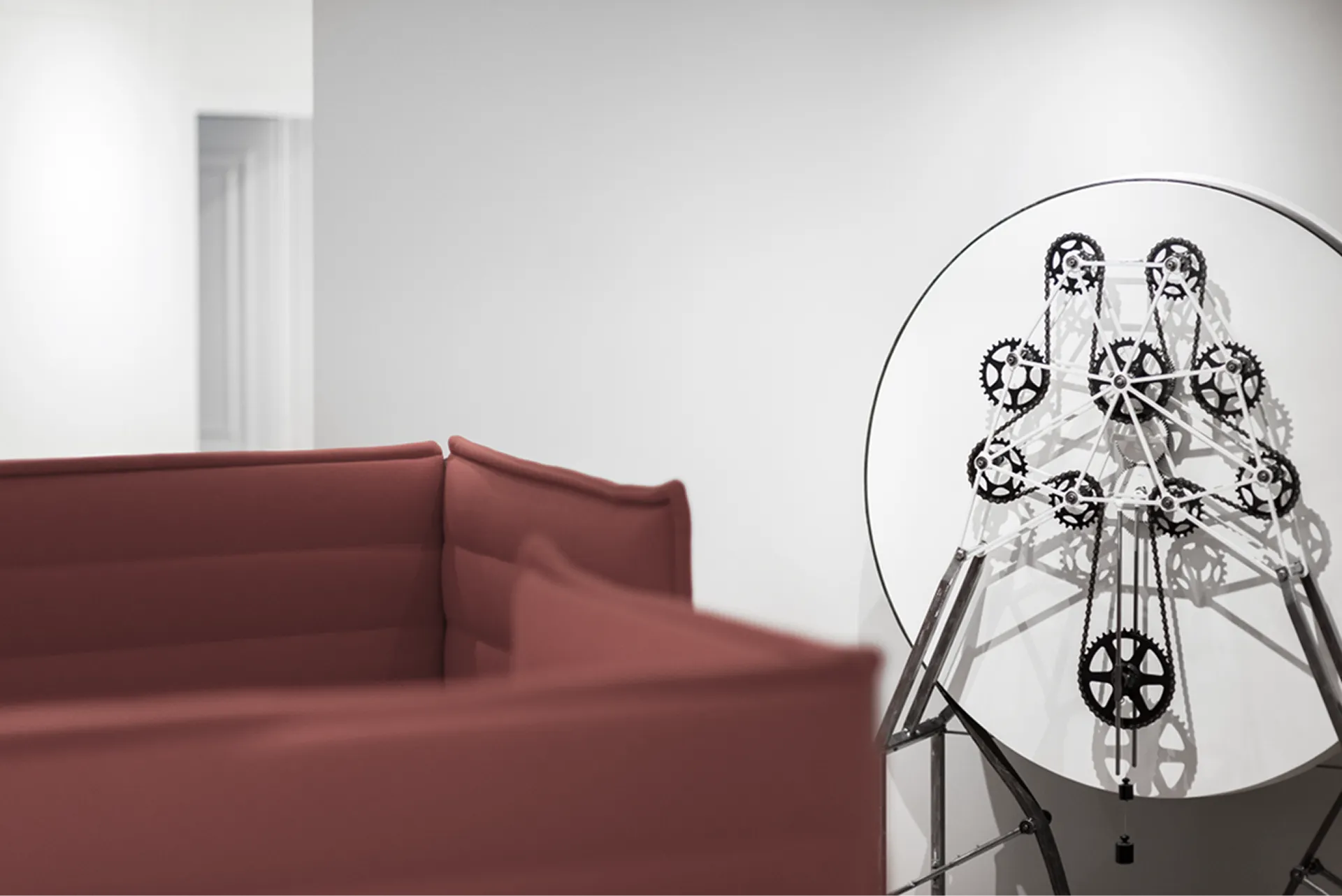 Locaux de CG Partners à Genève : canapé rouge et horloge sculpture à engrenages