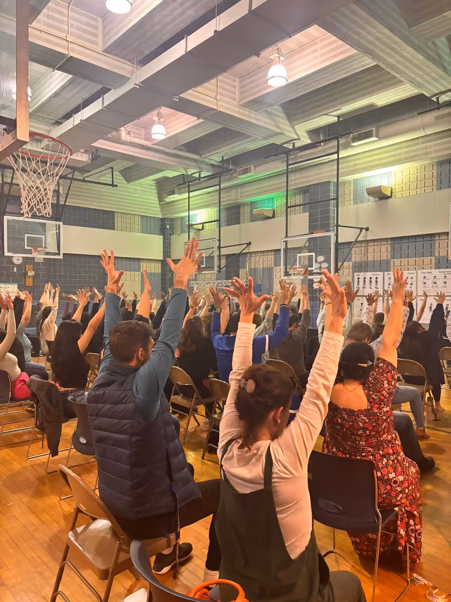 Parents raising hands during a school gymnasium community event