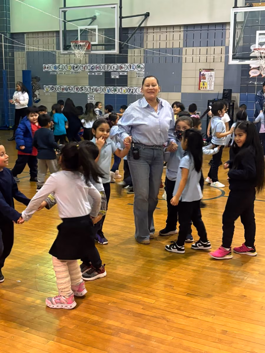 Teacher dancing with elementary students in school gymnasium