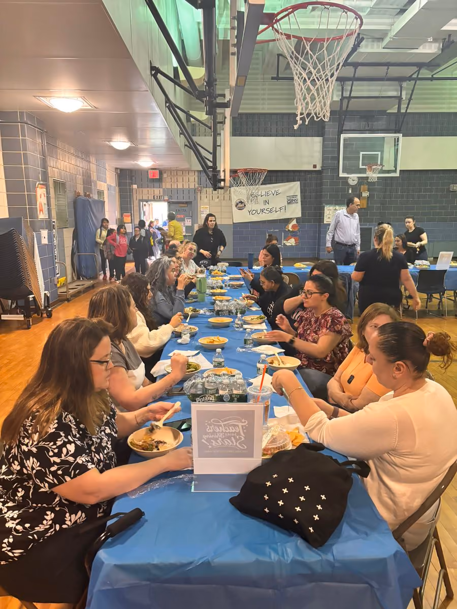Teachers and staff sharing a meal together in school gymnasium