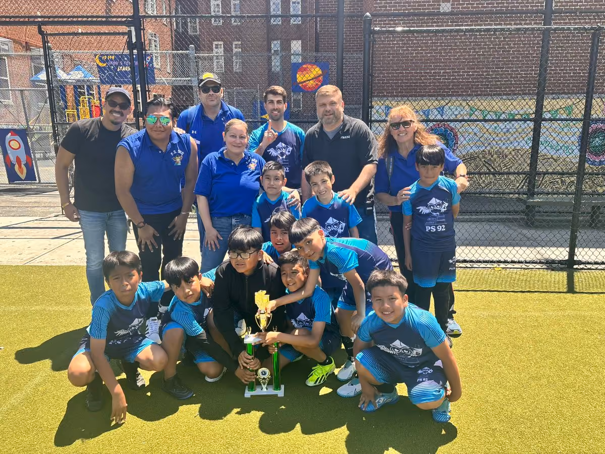 PS 92 students and staff celebrating with a sports trophy outdoors