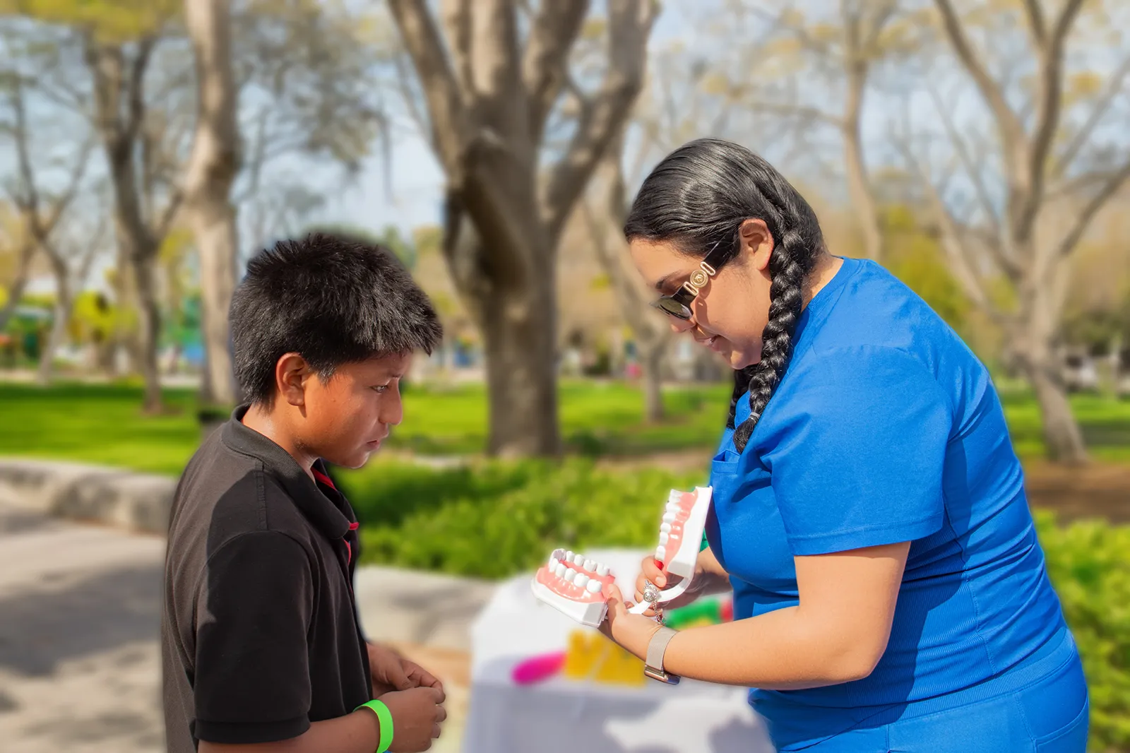 A dental health worker showing a boy a model of teeth during an outdoor community health education event.
