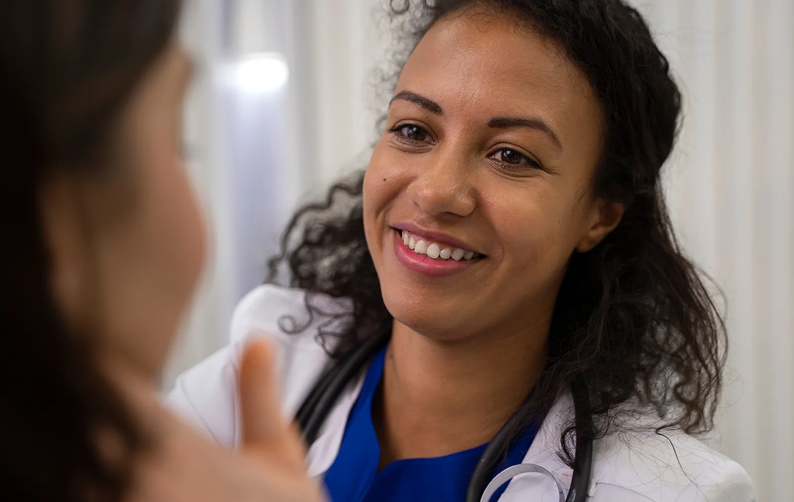 A smiling doctor in a white coat talking warmly with a patient.