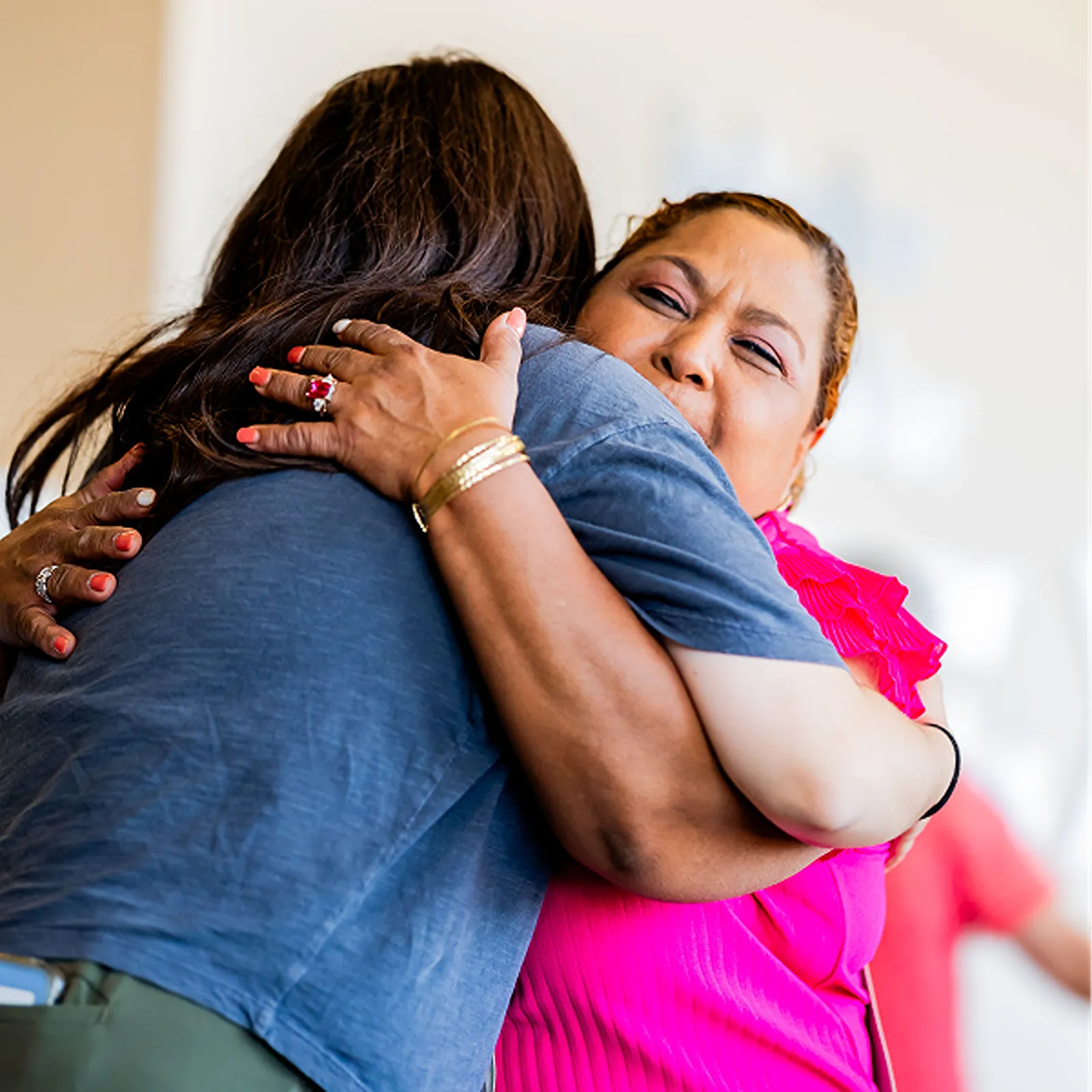 Two women embracing in a warm, emotional hug at a community event.