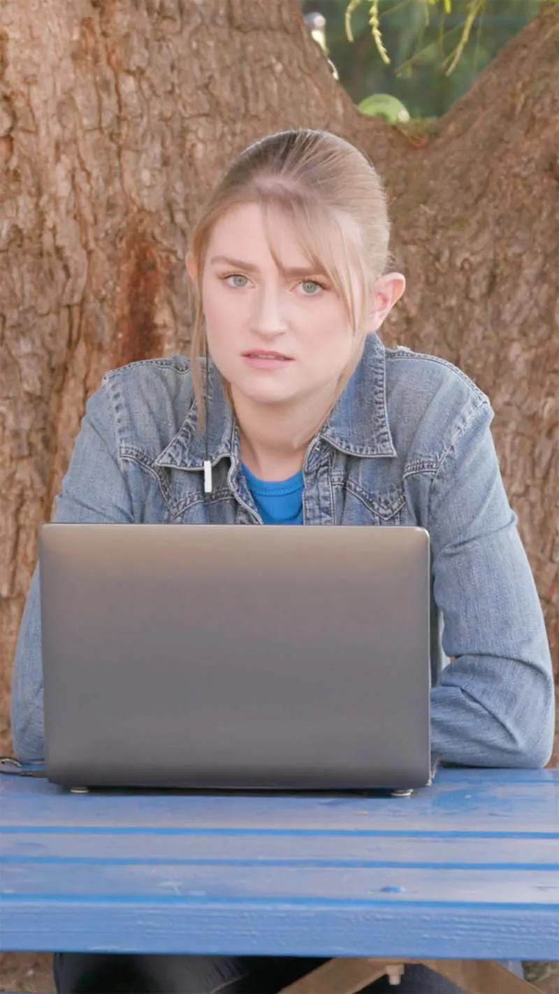 A young woman in the middle of studying on her laptop, looking concerned