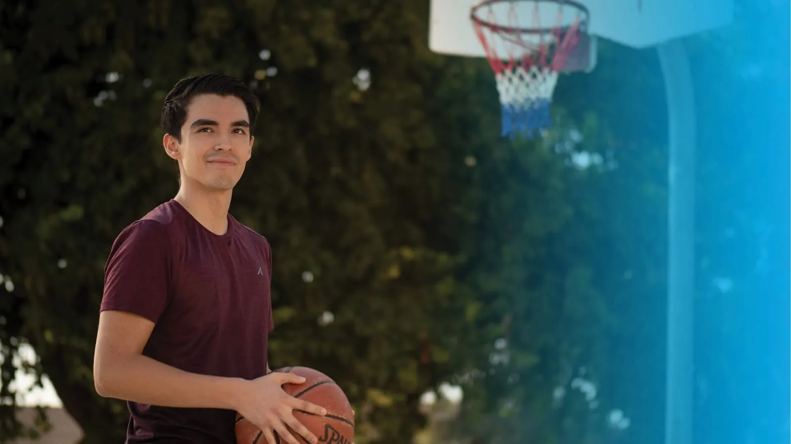 A young man playing basketball, smiling