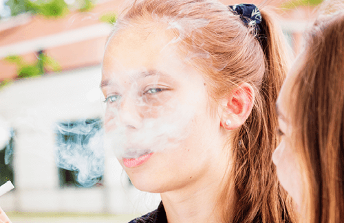A young teenage exhaling smoke