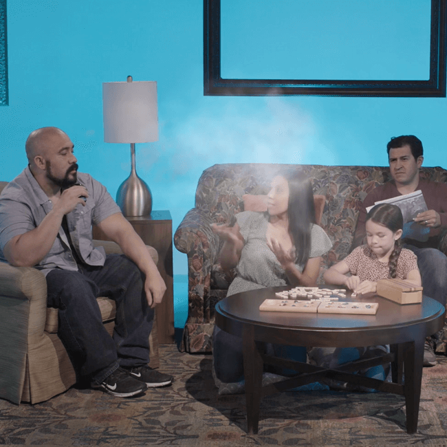 A person blowing smoke from a vaping device, in front of their whole family