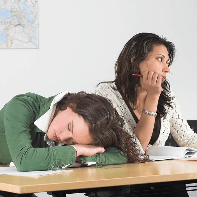 A teenager asleep at a school desk