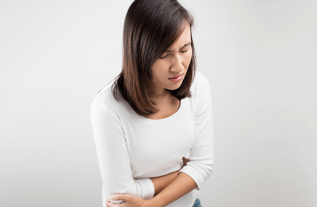 A woman in discomfort holding her stomach