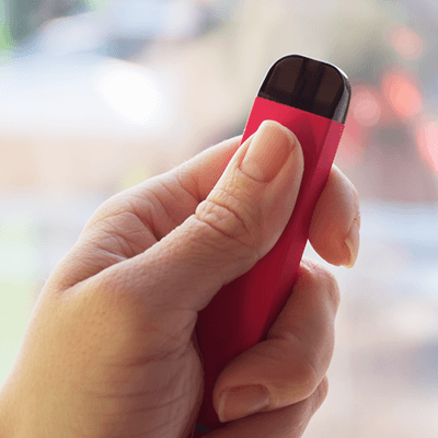 A hand holding a vaping device