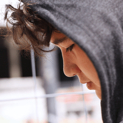 A young teen looking pensive, wearing a hoodie