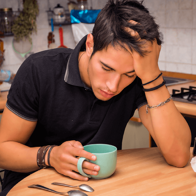 A teenager holding his head in his hand
