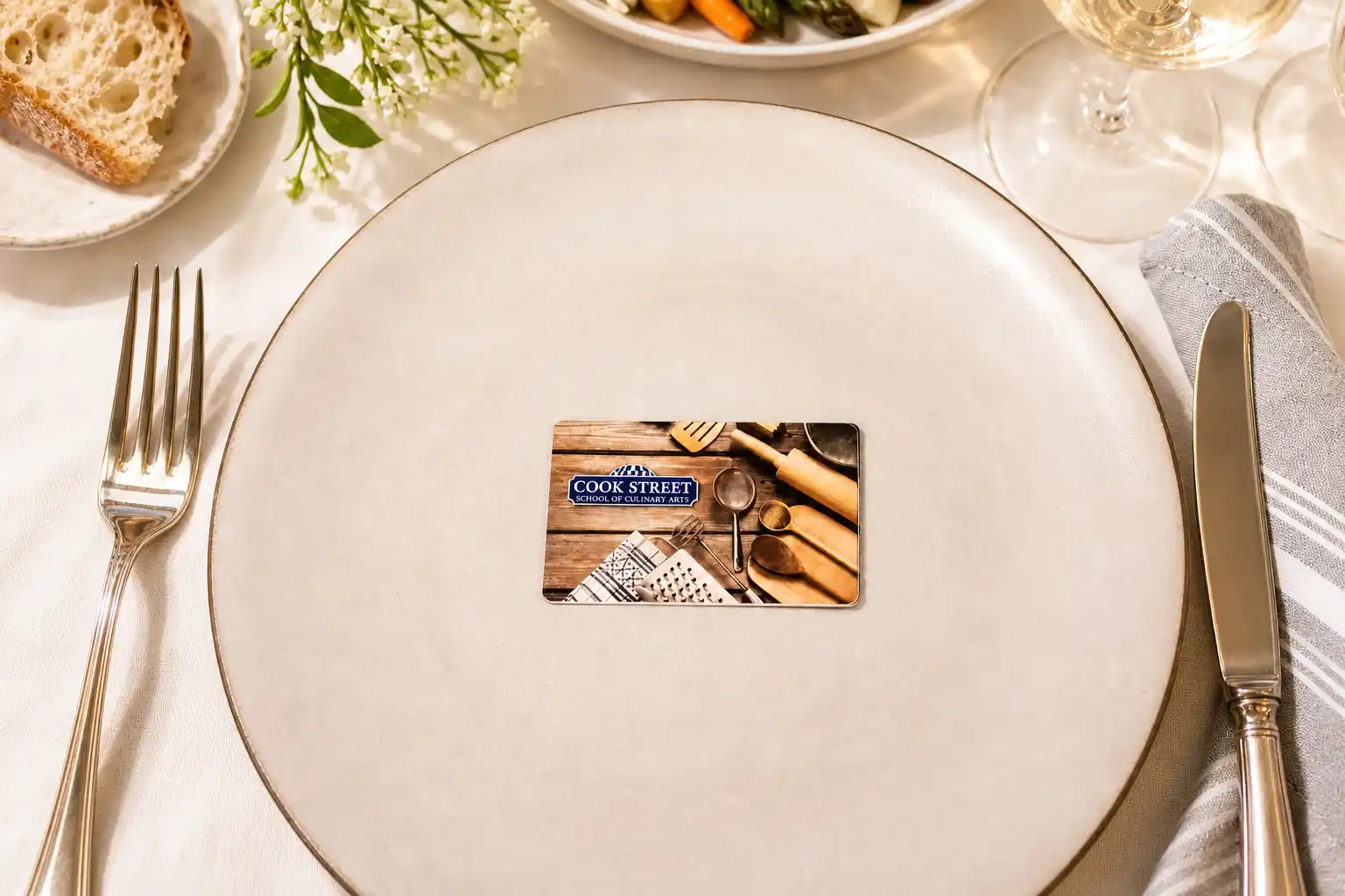 Cook Street gift card on an empty plate set with fork, knife, napkin, bread, and wine glass.