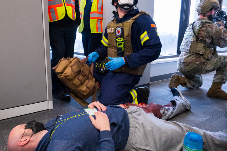 A paramedic with the rescue task force checks on a shooting “victim” as an 88th Security Forces Squadron Defender provides cover and exercise observers look on during an active-shooter exercise Feb. 23, 2022, at Wright-Patterson Air Force Base, Ohio. The exercise gave first responders, including police, fire and medical personnel, the opportunity to practice coordinating emergency actions and procedures.