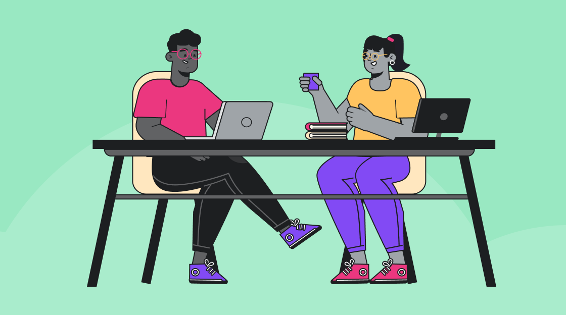 two people sitting at a table with laptops