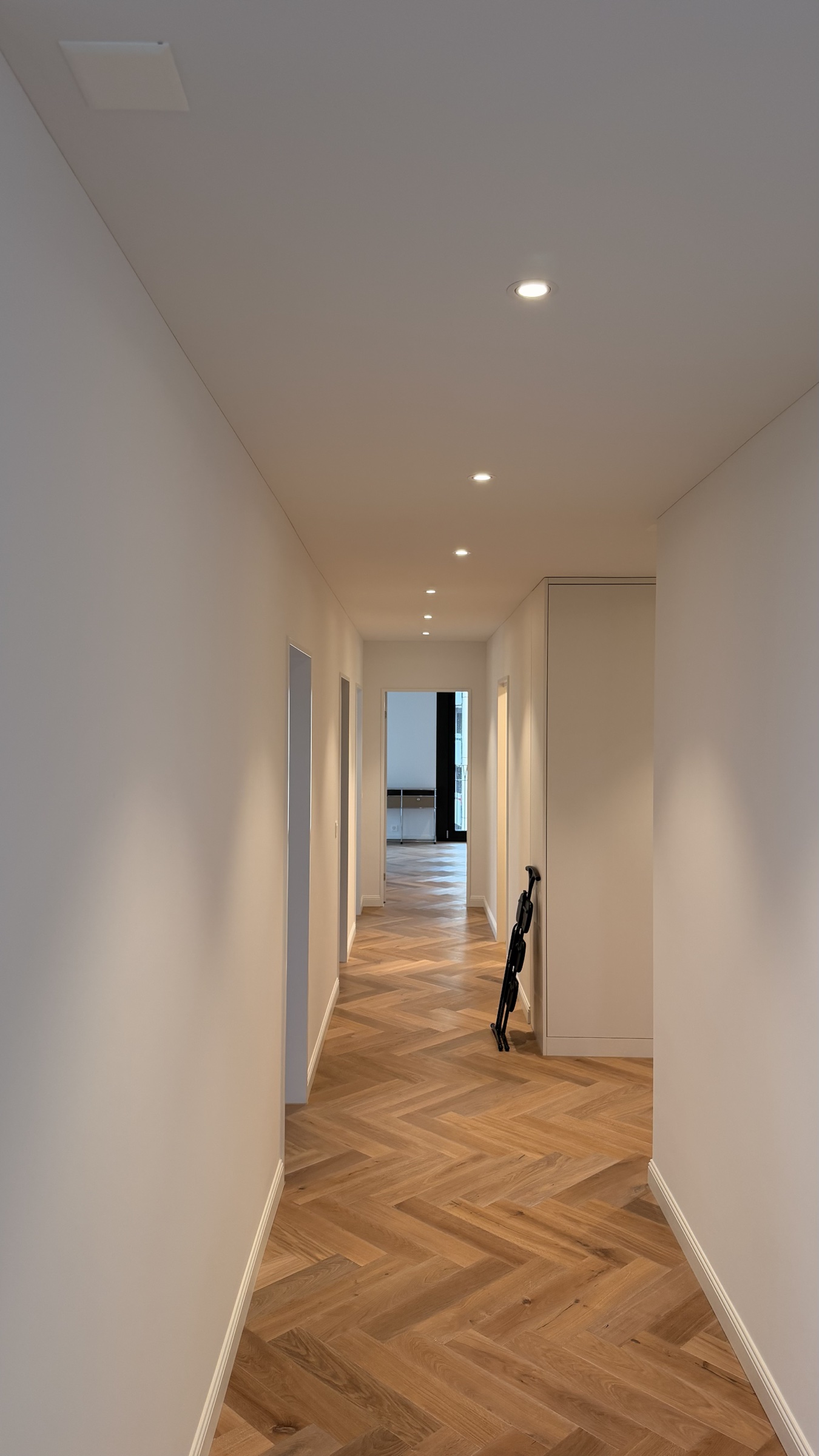 Vorher: langer Gang der Attikawohnung Uster mit regelmässigem Downlight-Raster