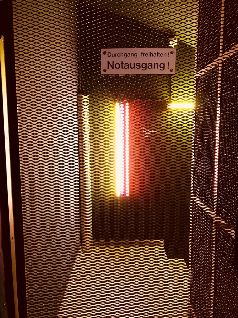 Farbige Fluoreszenzleuchten hinter industriellem Streckmetall