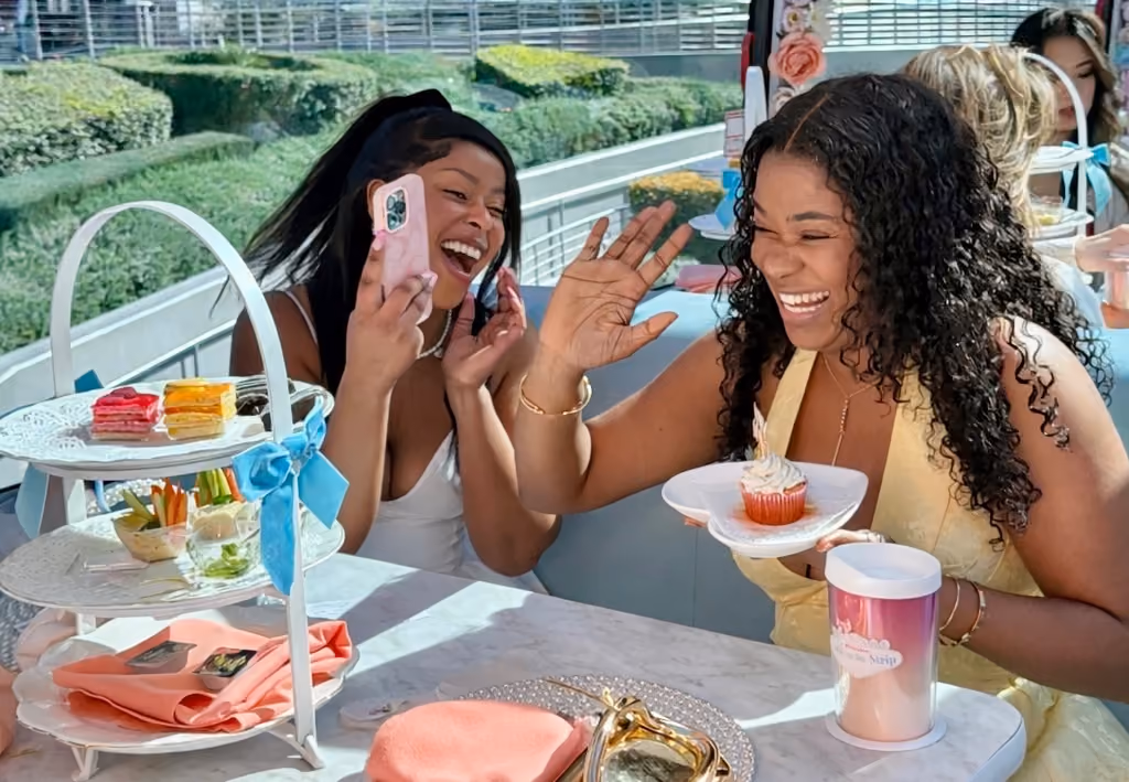 Two guests laughing and taking photos at their tea table