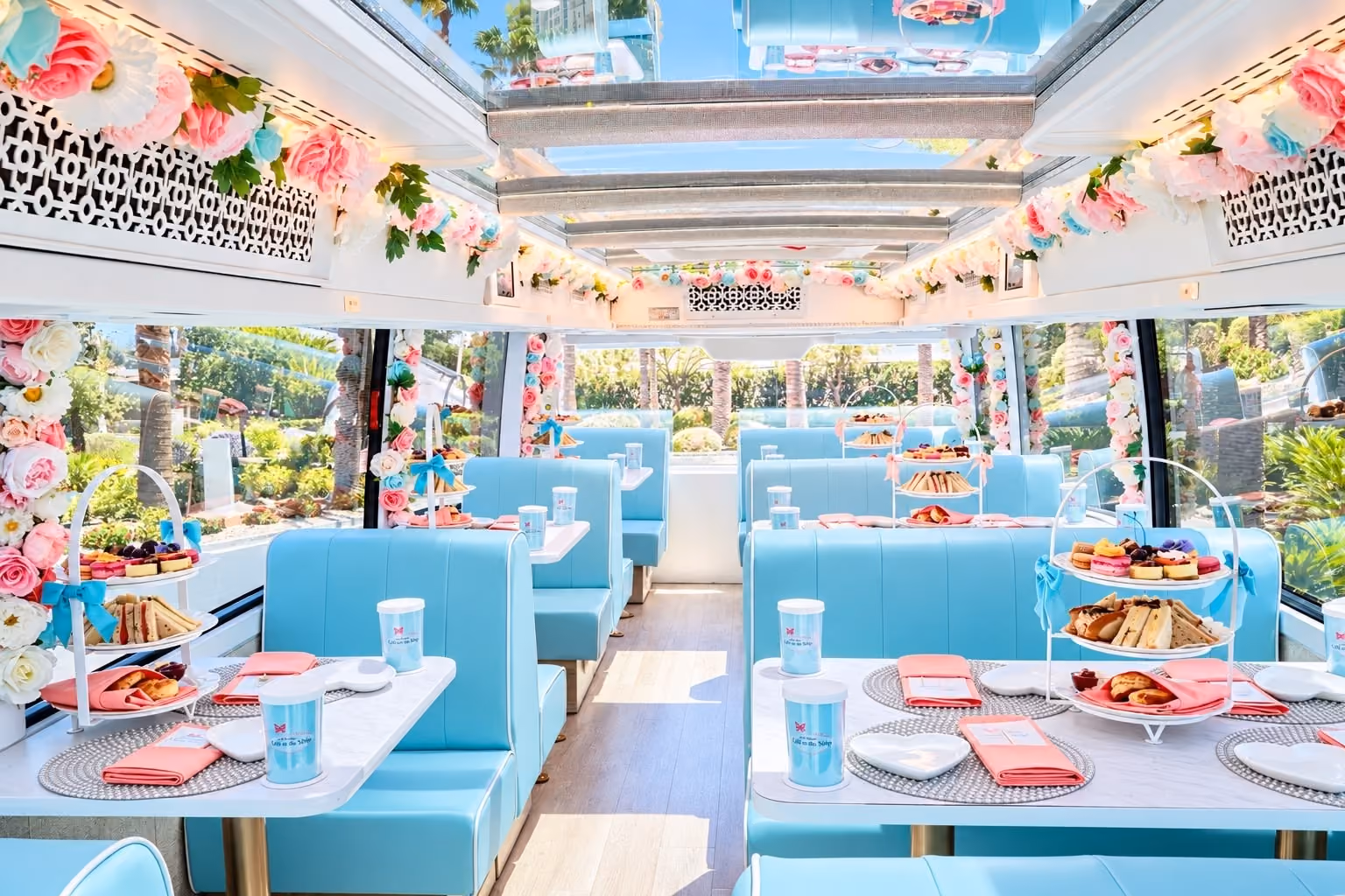 Plush blue booths set for afternoon tea inside the Cafe on the Strip double-decker coach