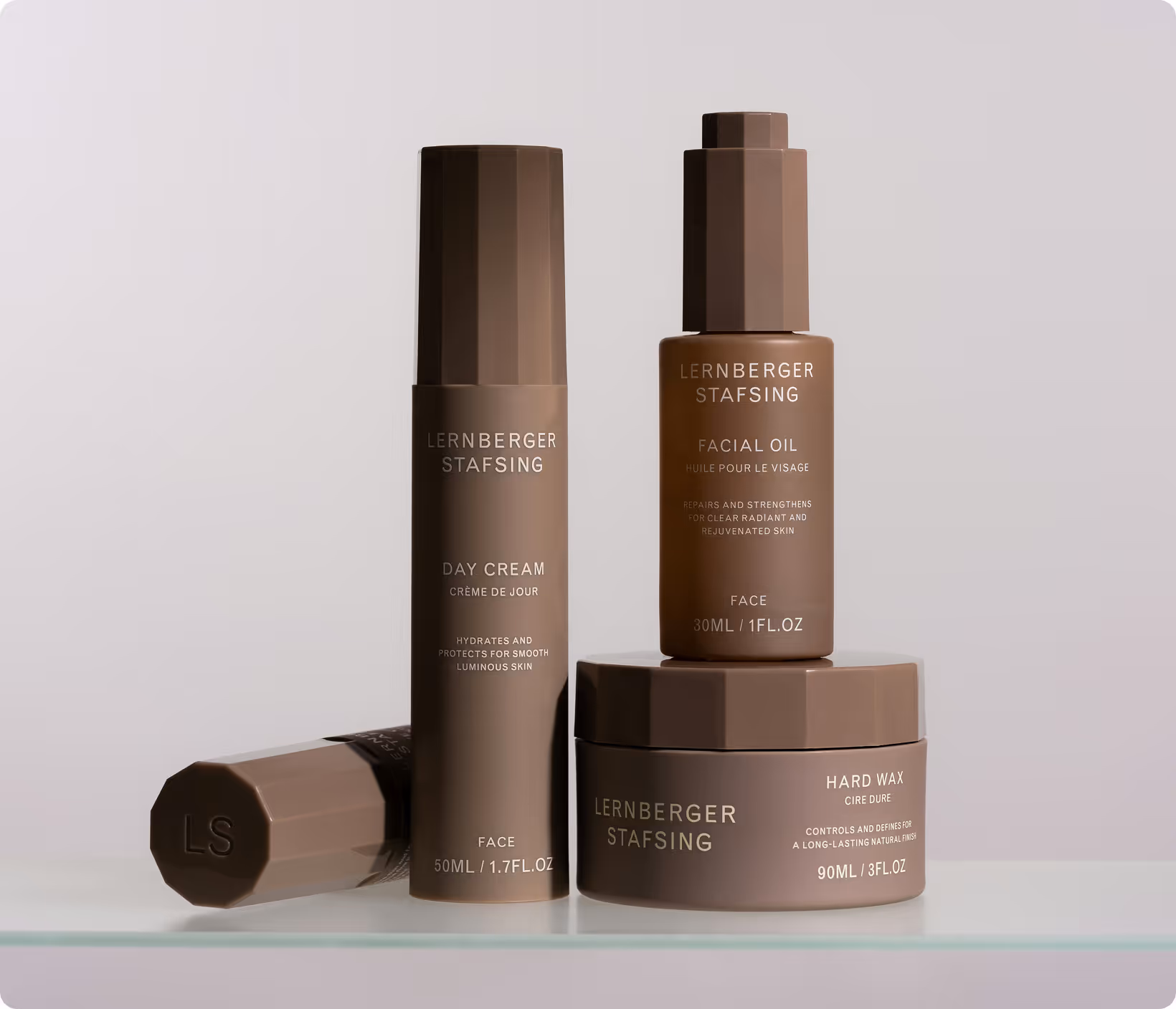 Set of three beige-brown cosmetic products labeled as Lehnberger Stafsing skincare on a glass surface with a plain light background.