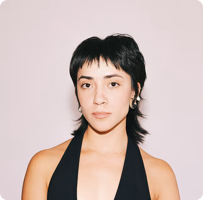 Woman with short black hair wearing a black halter top against a plain light background.