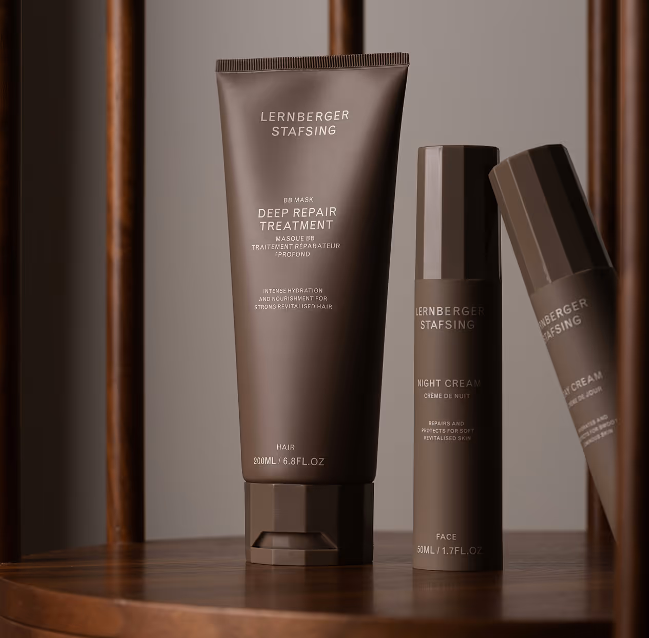 Brown tubes of Lernberger Stafsing Deep Repair Treatment hair mask and Night Cream face moisturizer on a wooden surface.