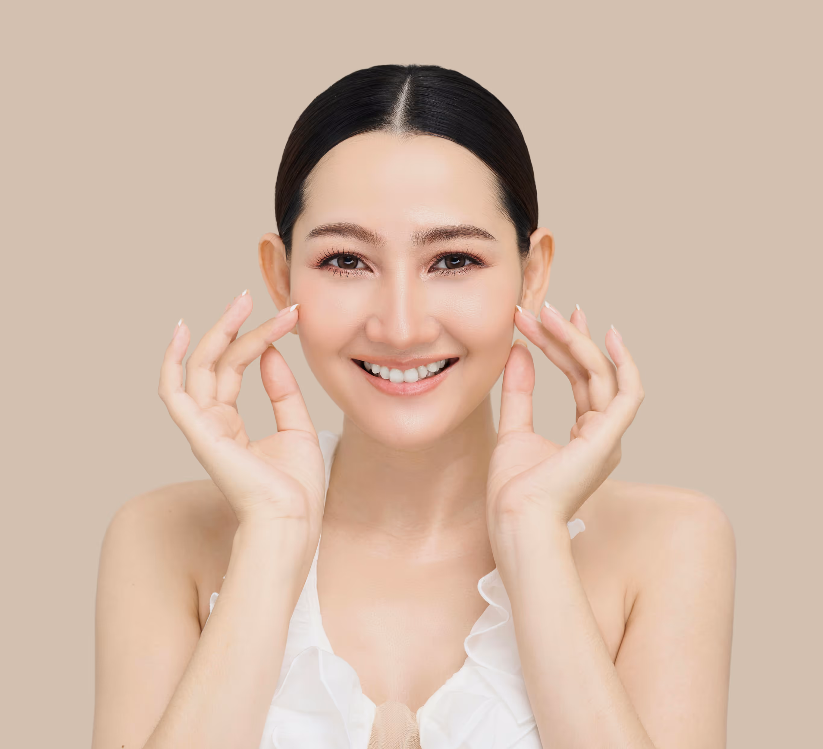 Smiling woman with a center-parted hairstyle touching her face against a beige background.