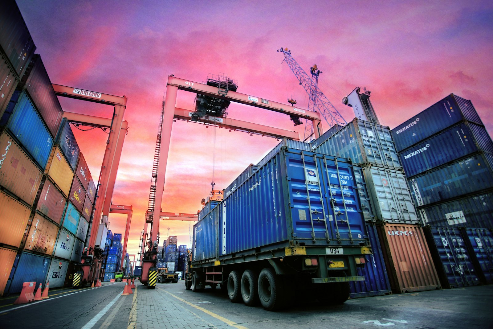 Shipping containers stacked at a busy port at sunset, representing global trade logistics