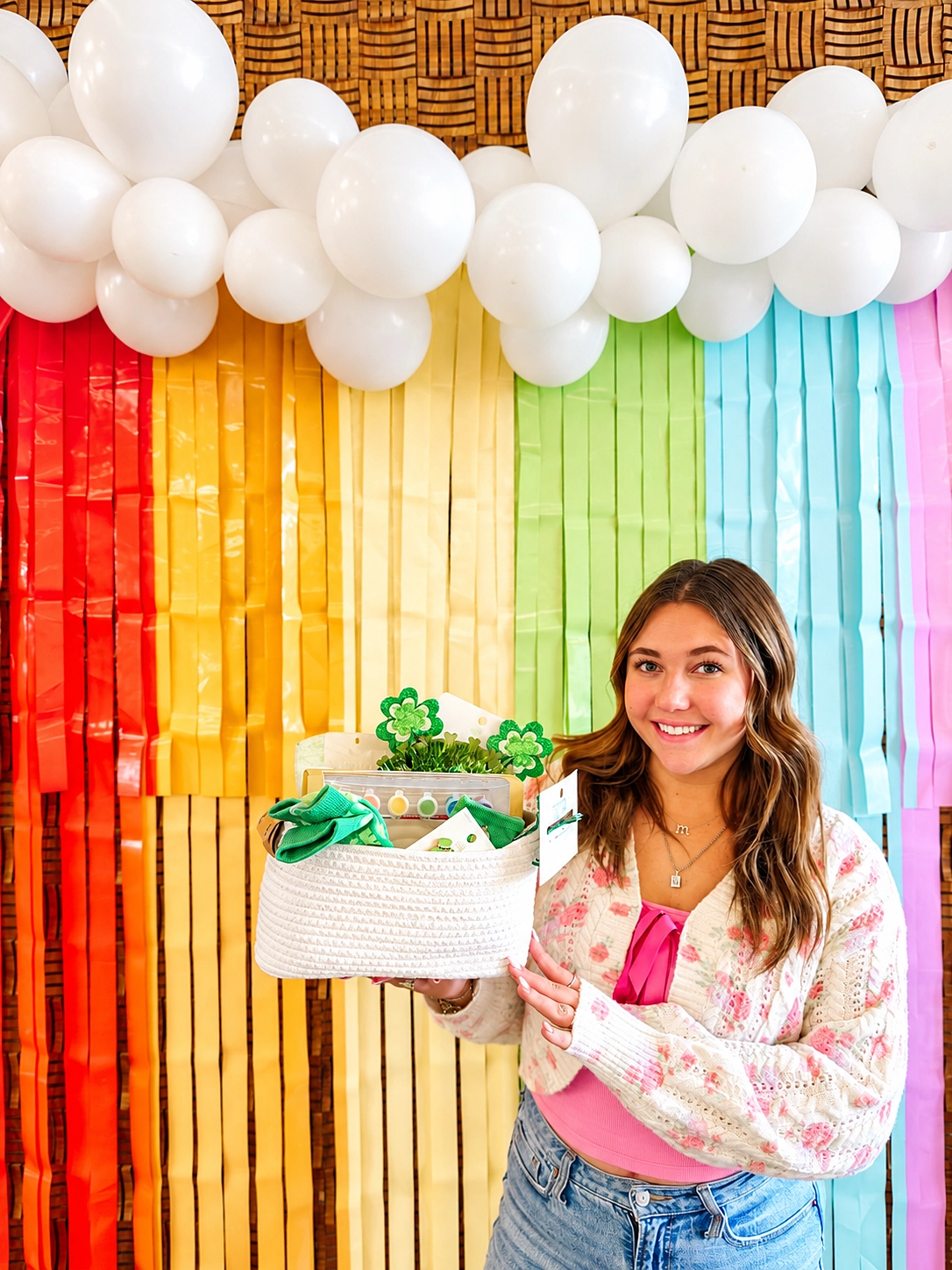 Team member holding a gift basket by a rainbow backdrop