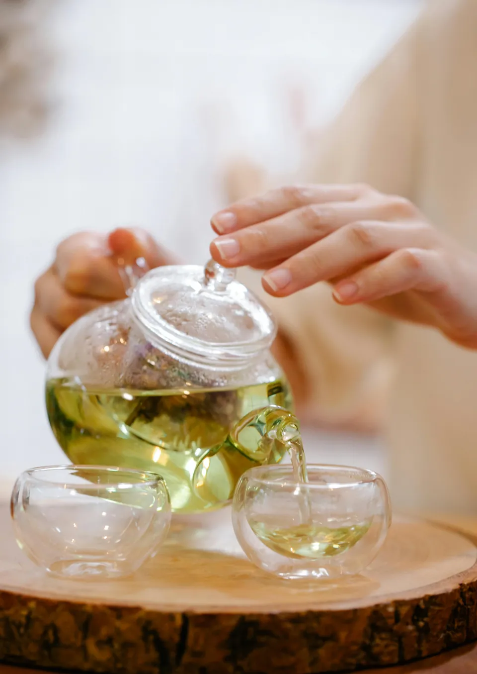 Tea being poured from a glass teapot into a small cup