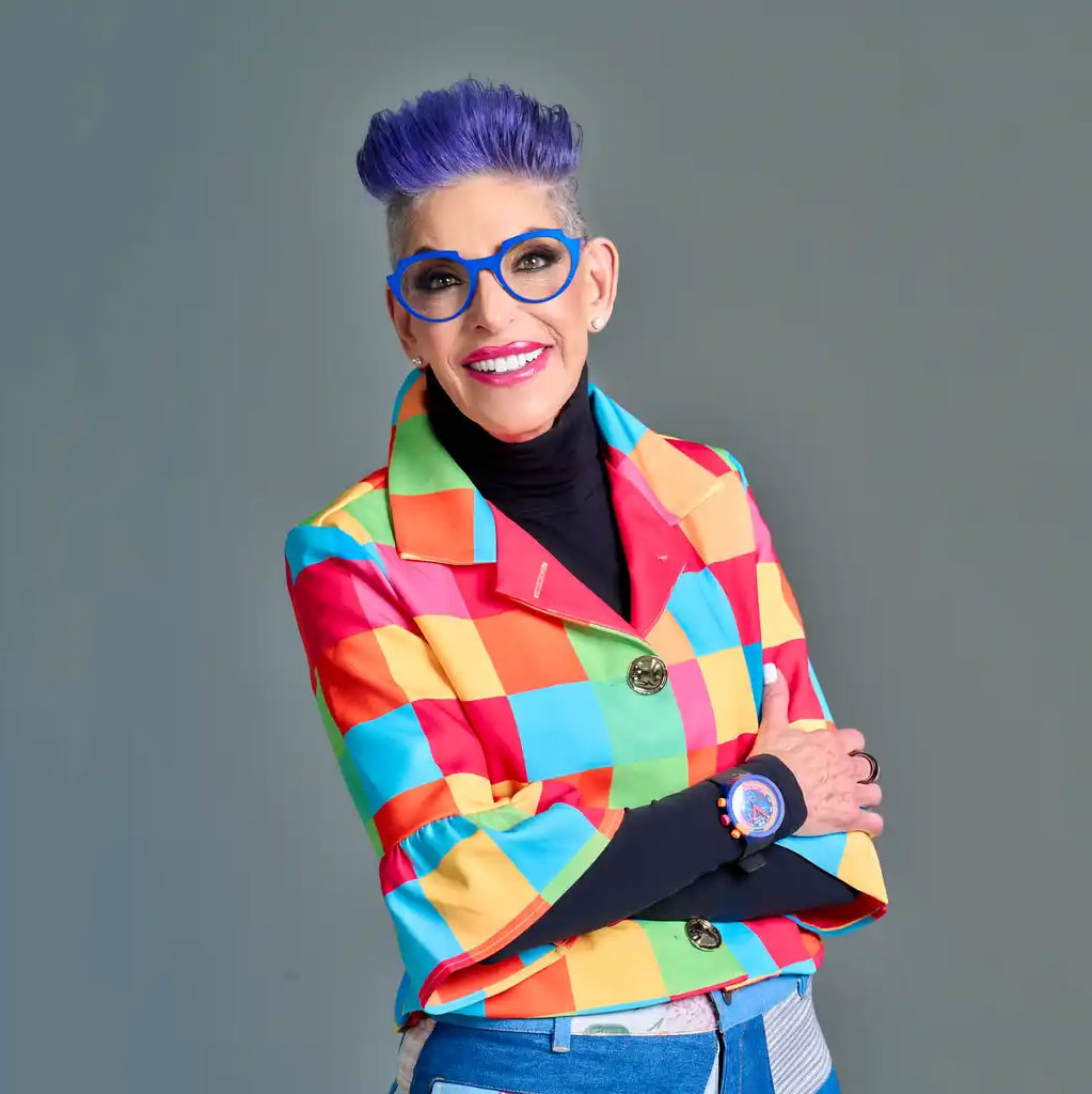 Barbra Jo Batterman in a colorful blazer and blue glasses with signature purple hair