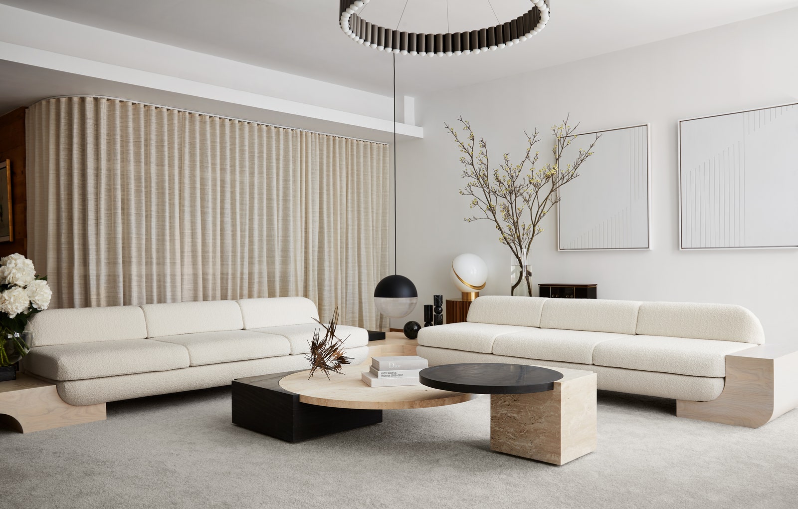 Minimalist living room with two white sofas, round coffee tables, floor lamp, and large branch decor
