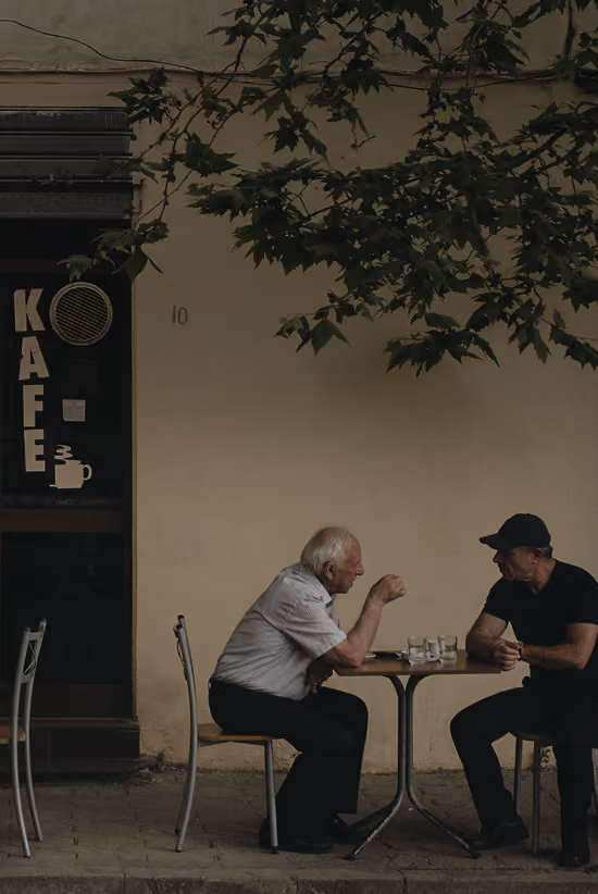 elderly people sitting at a small table outside a café
