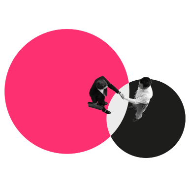 Overhead view of two men shaking hands while standing on overlapping circles colored pink and black on a white background.